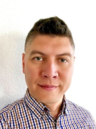 Vladimir smiling at the camera with a white background